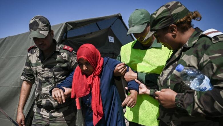 Military personnel attend to a survivor of an earthquake.