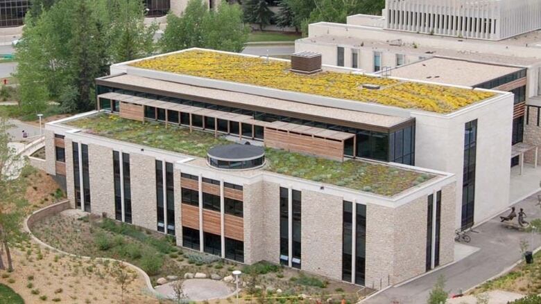 An aerial view of two large buildings whose roofs are covered in vegetation.