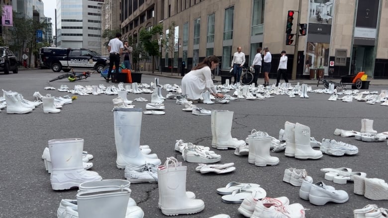 Dozens of pairs of white shoes laid out at a Montreal intersection. 