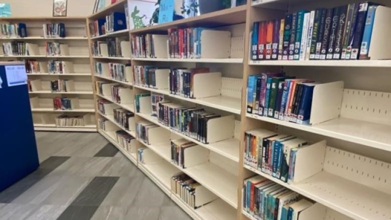 Many sets of bookshelves in a library which are only partially full of books.