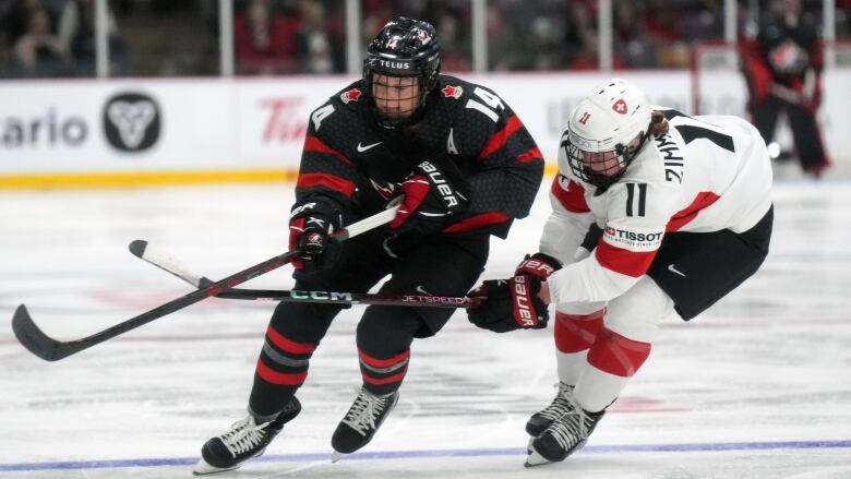 A hockey player skates with the puck past an opponent.