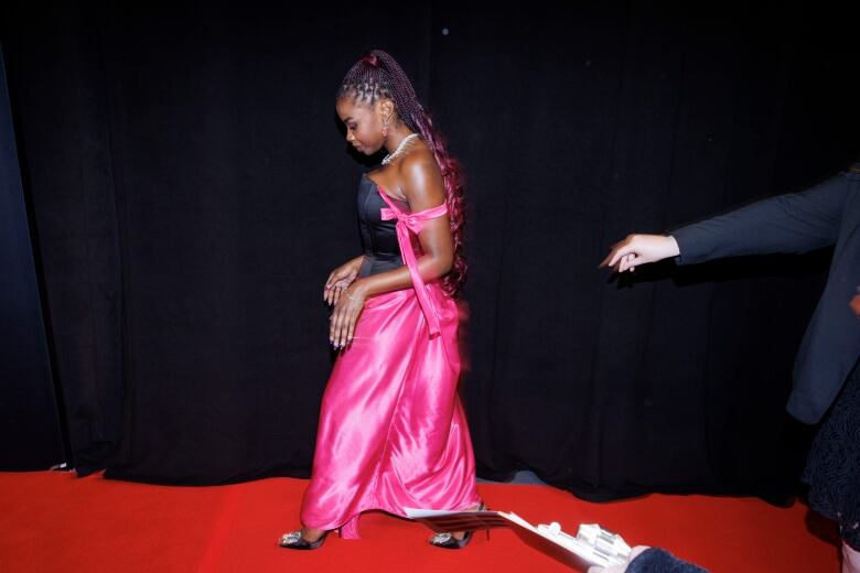 A Black actor in strapless pink gown walking the red carpet at TIFF.