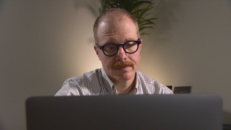 A picture of Dr. Aaron Orkin, public health and emergency physician and researcher at the University of Toronto, looking at a laptop reviewing the data that CBC News compiled.