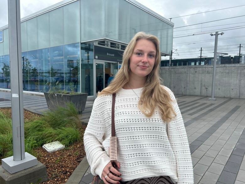 A woman poses for a photo outside a light-rail station. 