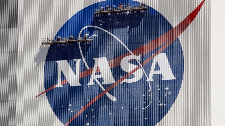 Workers on scaffolding repaint the NASA logo at the Kennedy Space Center in Cape Canaveral, Fla.