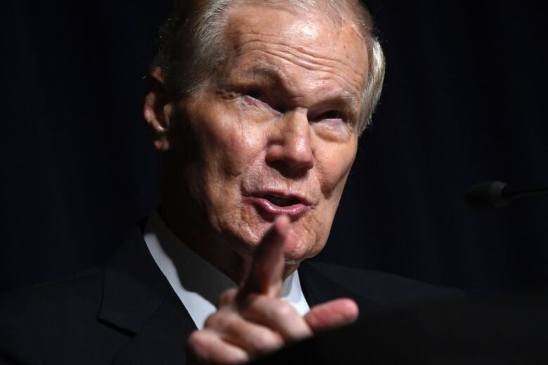 A man in a suit speaks to reporters during a media briefing.