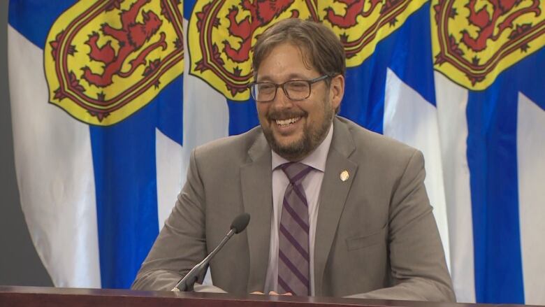 A man with a beard and glasses sits at a table.