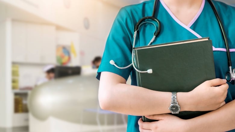 A stock photo of a nurse holding books. 