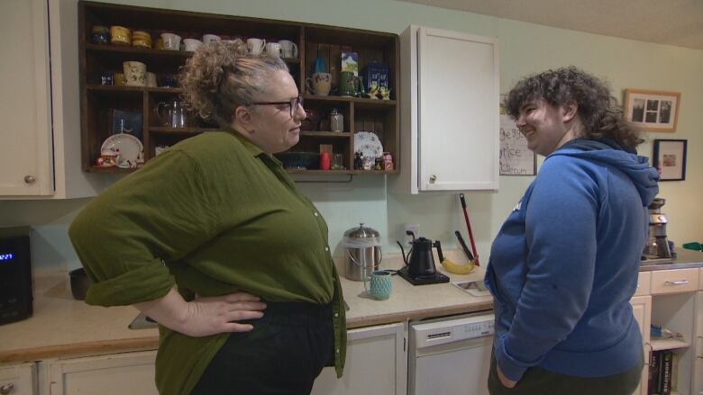 A mom and her teenager stand in a kitchen.