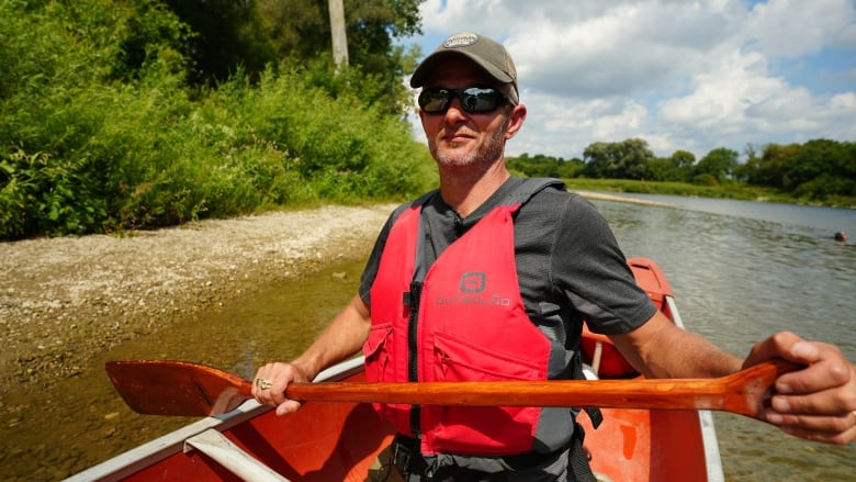 Close up photo of Ben Chamberlain in a canoe, wearing a lifejacket and holding a paddle. 