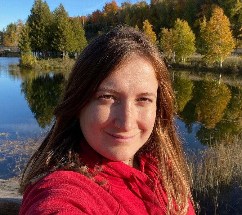 A selfie of a woman in front of fall foliage