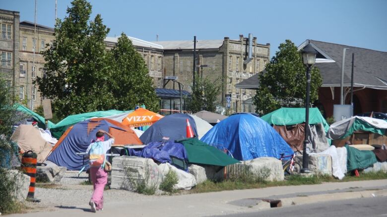 A person walks by tents set up in a vacant lot