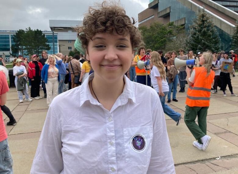 student wearing white standing in a protest.