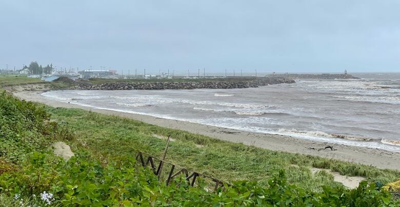 A coastal area with large waves crashing against a rock breakwater.