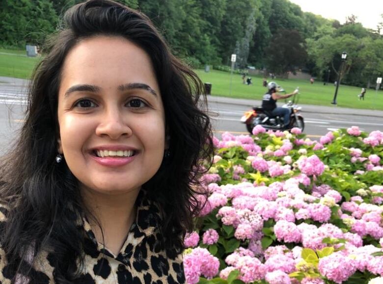 Woman takes selfie in front of flowers.