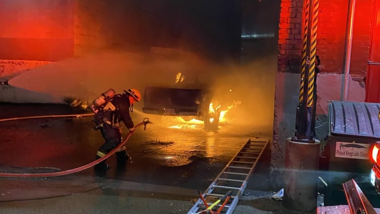 Firefighters spray water on a pickup truck that is burning.