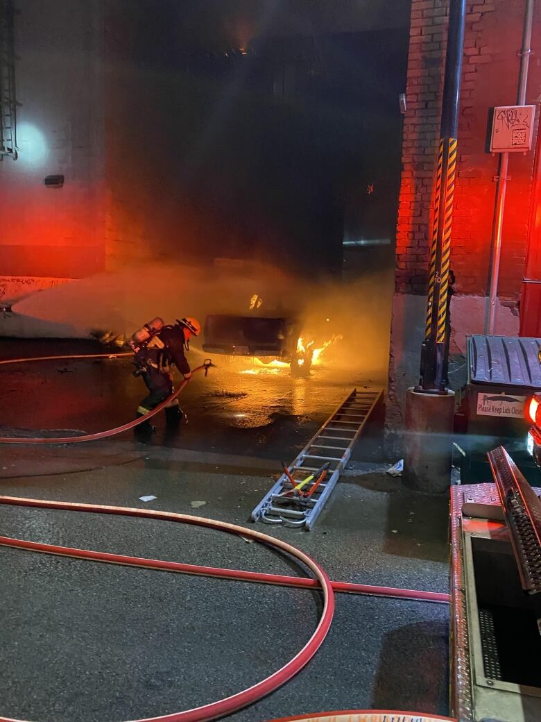 Firefighters spray water on a pickup truck that is burning.