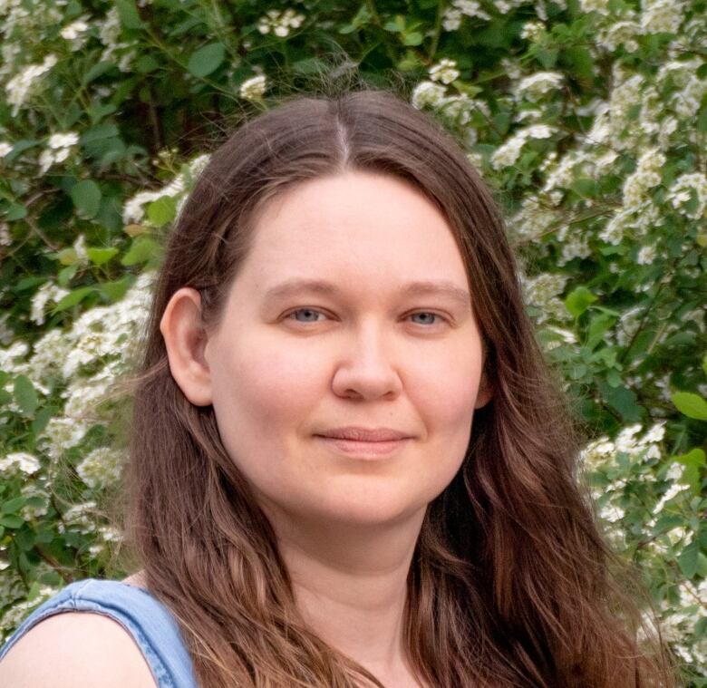 A headshot of a woman in front of a flowering background. 