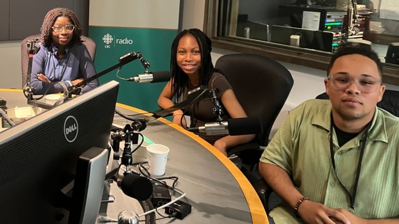 Three Black students, two young women and one young man, sit in a recording booth at CBC. 