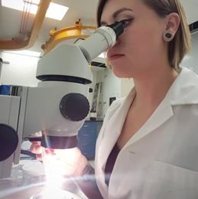 A woman looks through a microscope.