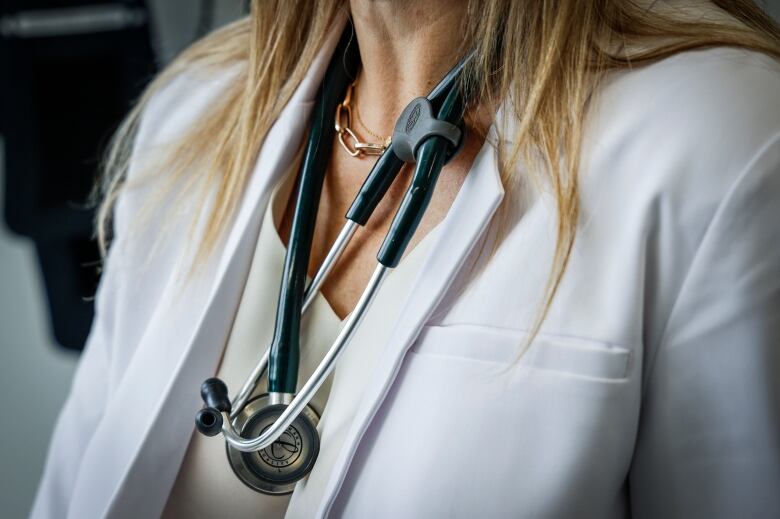 A doctor wears a lab coat and stethoscope in an exam room at a health clinic in Calgary, Friday, July 14, 2023.