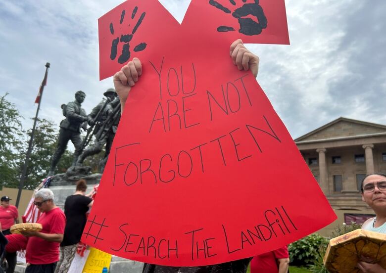 A protester in Charlottetown holds a poster in the shape of a red dress, which has become a symbol calling attention to missing or murdered Indigenous women and girls across Canada.