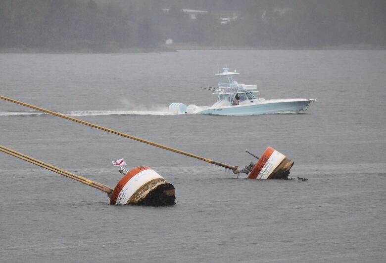 A small pleasure craft motors past in the background as ropes tug on two mooring anchors in the water known as dolphins.