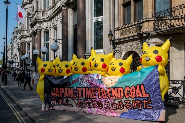 Protesters in Pokemon costumes hold a banner protesting the use of coal in Japan.