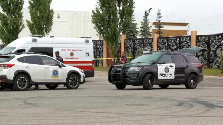 A police car and fire truck are parked in a parking lot.