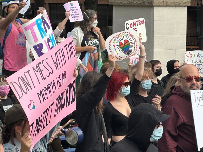 A group of people holding signs are shown.