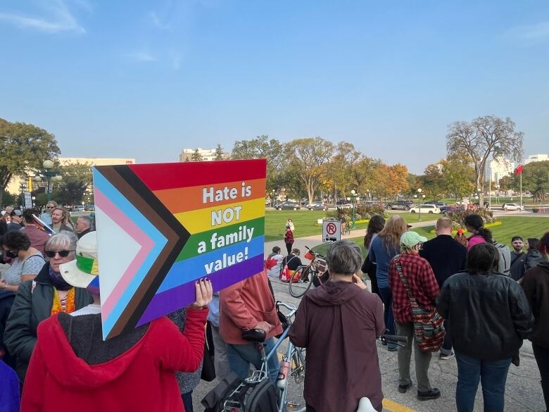 A person in a crowd holds a sign saying 'Hate is not a family value.'