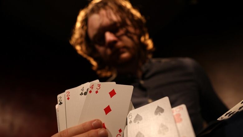 A man with his face out of focus fans out some playing cards.