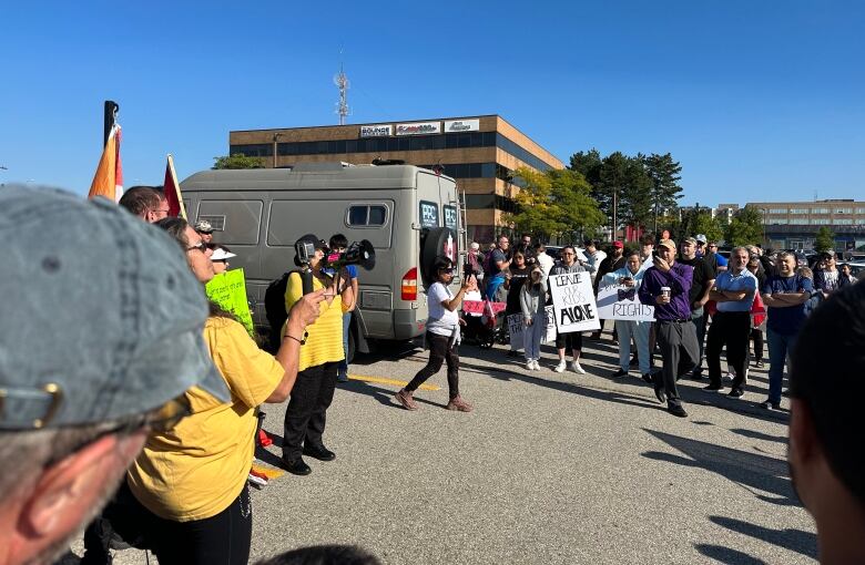 A crowd standing, listening to someone with a bullhorn.