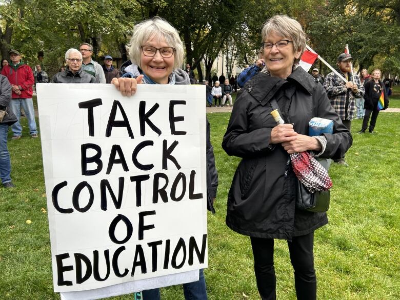 Two elderly white women holding a placard.