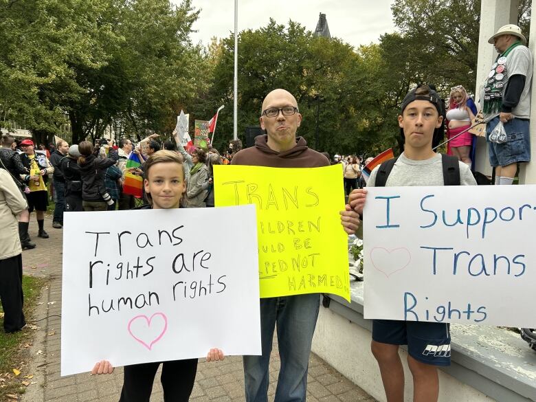 A bald man standing in between two young boys.