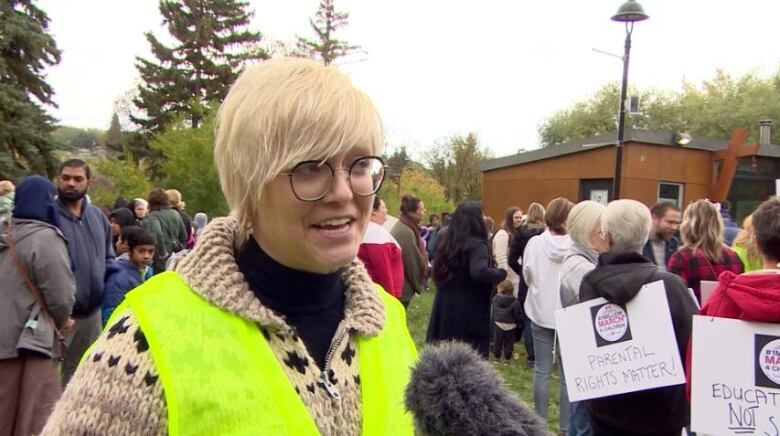 A woman in a blond hair and nuon vest.