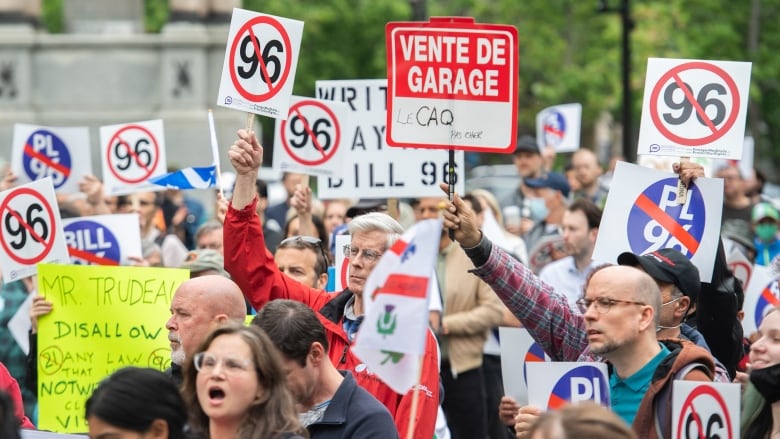 Protesters holding signs complaining about Bill 96