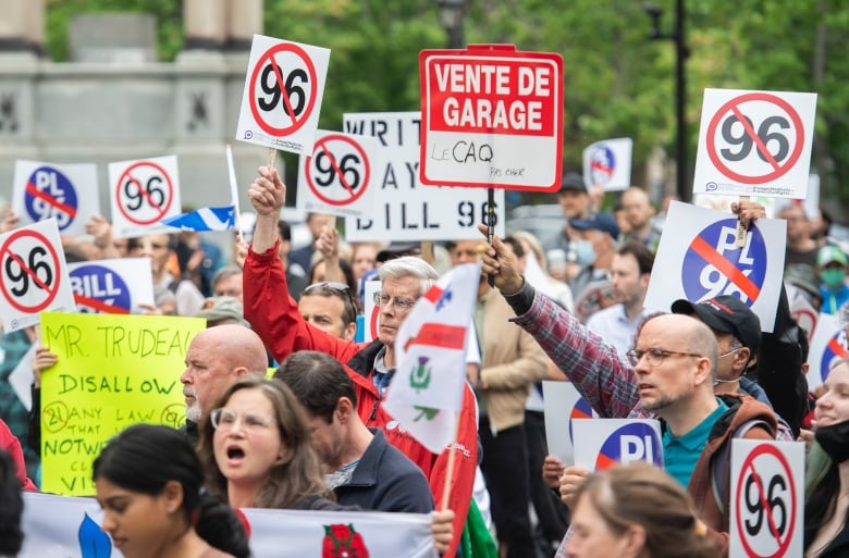 Protesters holding signs complaining about Bill 96