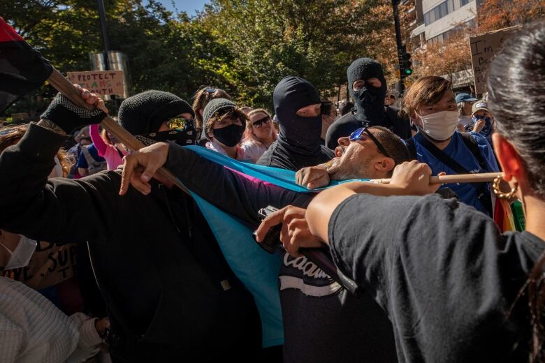 A man appears to be caught between two people who are shoving him