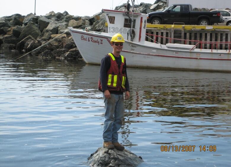 Man standing on a rock surrounded by water.