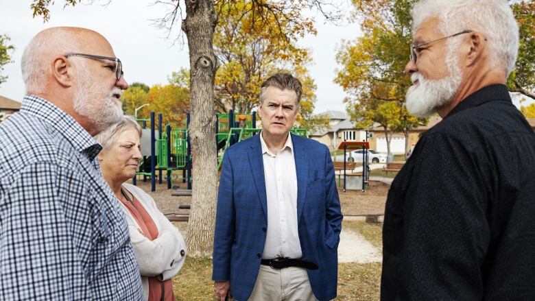 Four people stand in a circle by park.