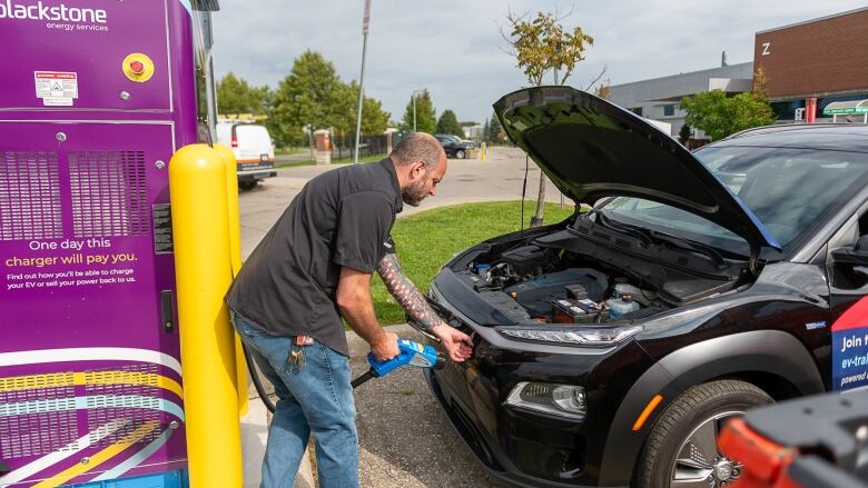 man plugs in electric car