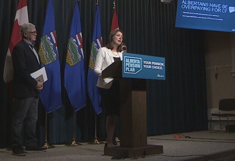 A woman stands at a lectern with a sign saying 