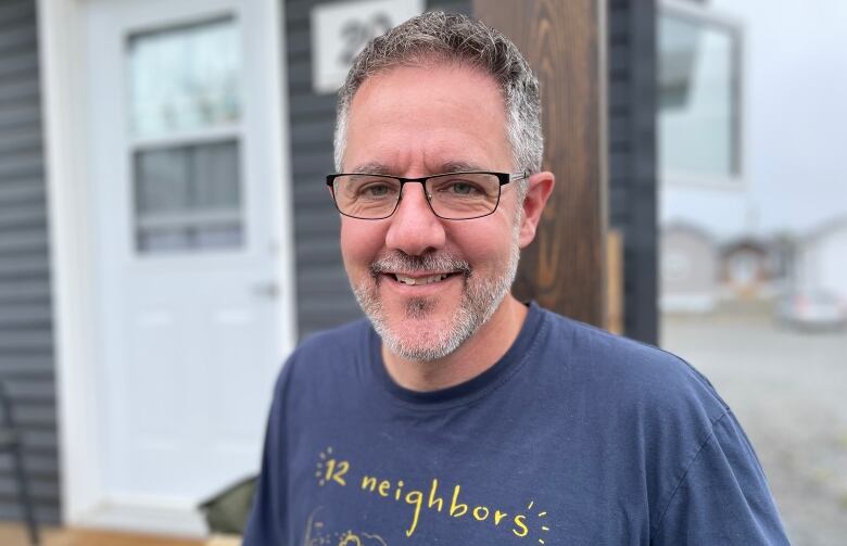 A man smiling in a blue shirt that says 