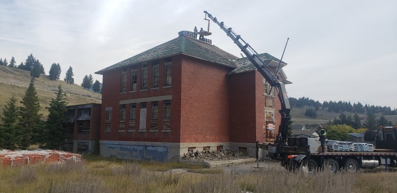 A red brick building with a crane nearby. 