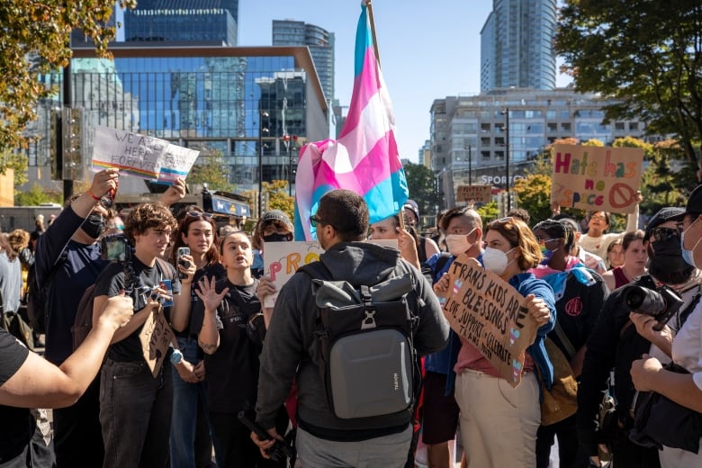 People with signs that say hate has no space and trans kids are blessings speak to a person