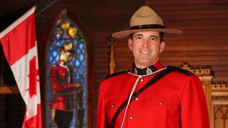 A man in an RCMP red outfit stands smiling. 