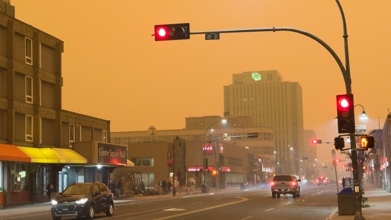 cars driving on a road with a dark orange sky.