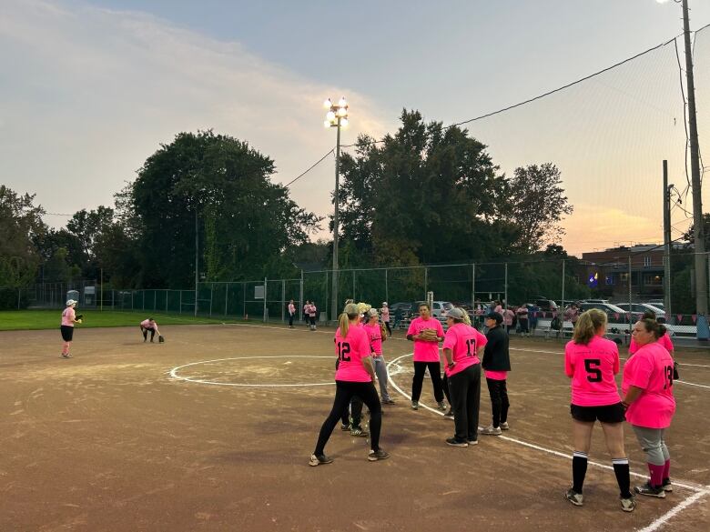 Women in neon pink shirts playing softball. 