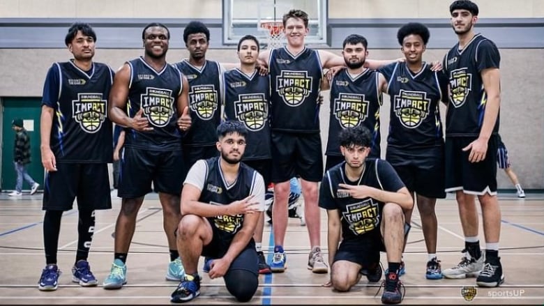 A group of young men pose for a picture on a basketball court.